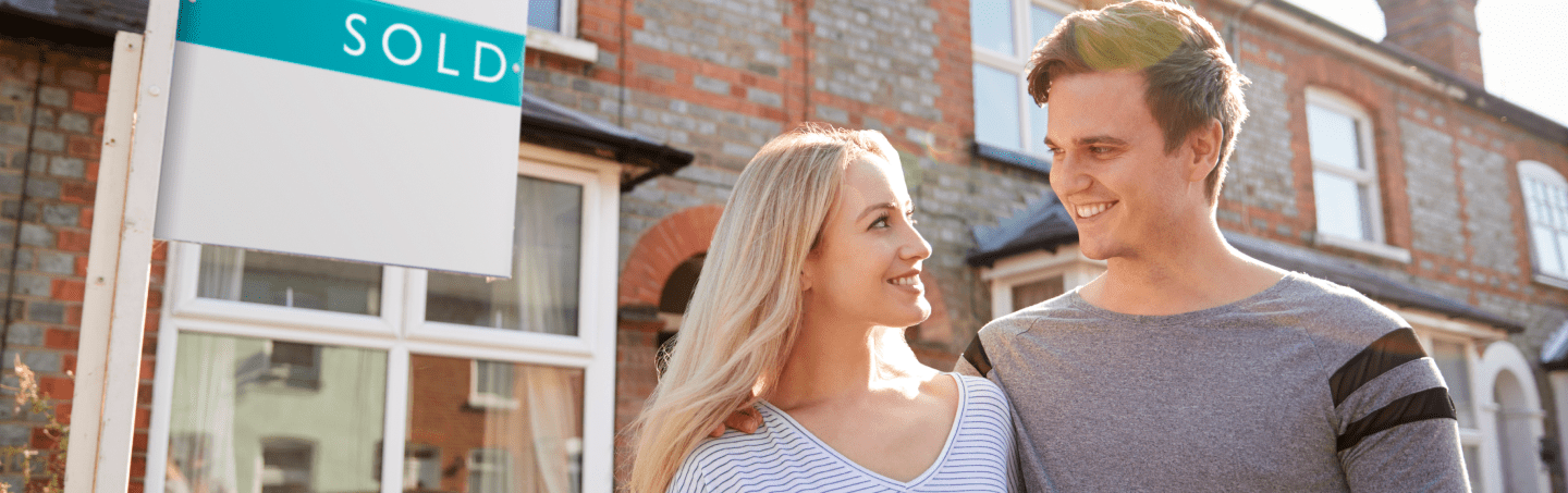excited-couple-standing-outside-new-home